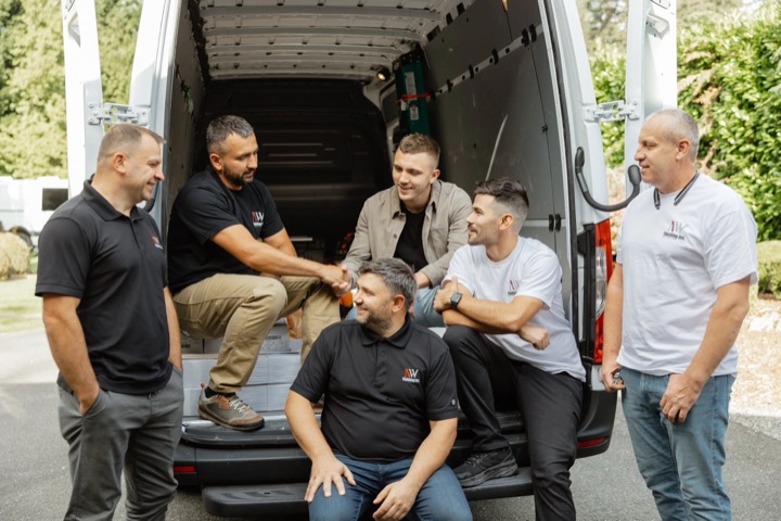 The NW Finishing crew gathered at the back of a company work van.