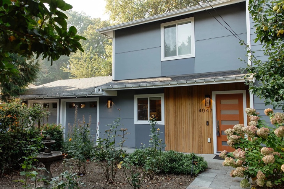 Exterior of a Bellevue home addition with grey siding, a cedar-clad entry and new landscaping.