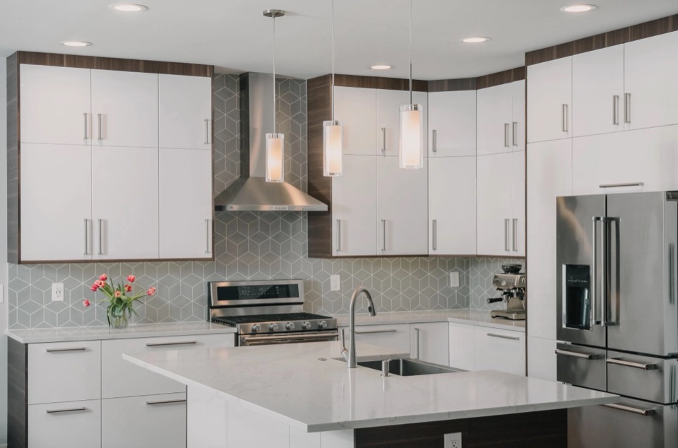 Residential Oasis in Fife: a bright kitchen with white cabinetry, grey tile backsplash and a quartz island.