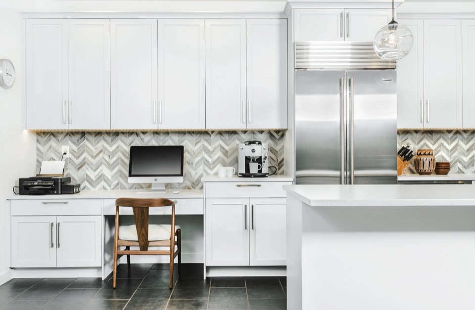 White & Light in Seattle: a white shaker kitchen with a herringbone tile backsplash, quartzite counters and a built-in desk.