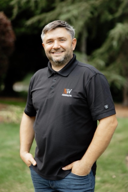 Portrait of Ivan Turchik, General Manager of NW Finishing, standing outdoors in a branded polo shirt.